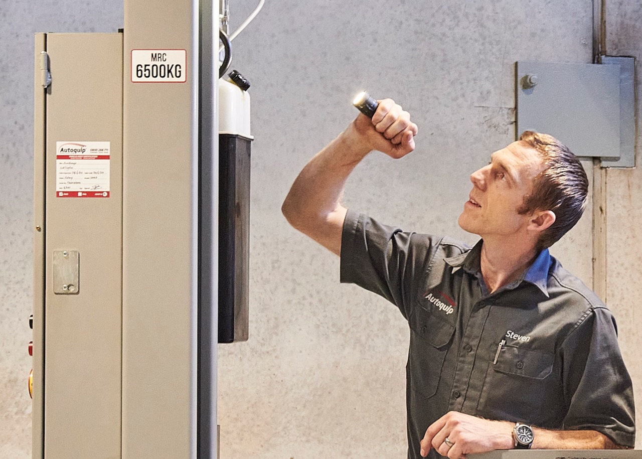 Autoquip technician inspecting a vehicle hoist